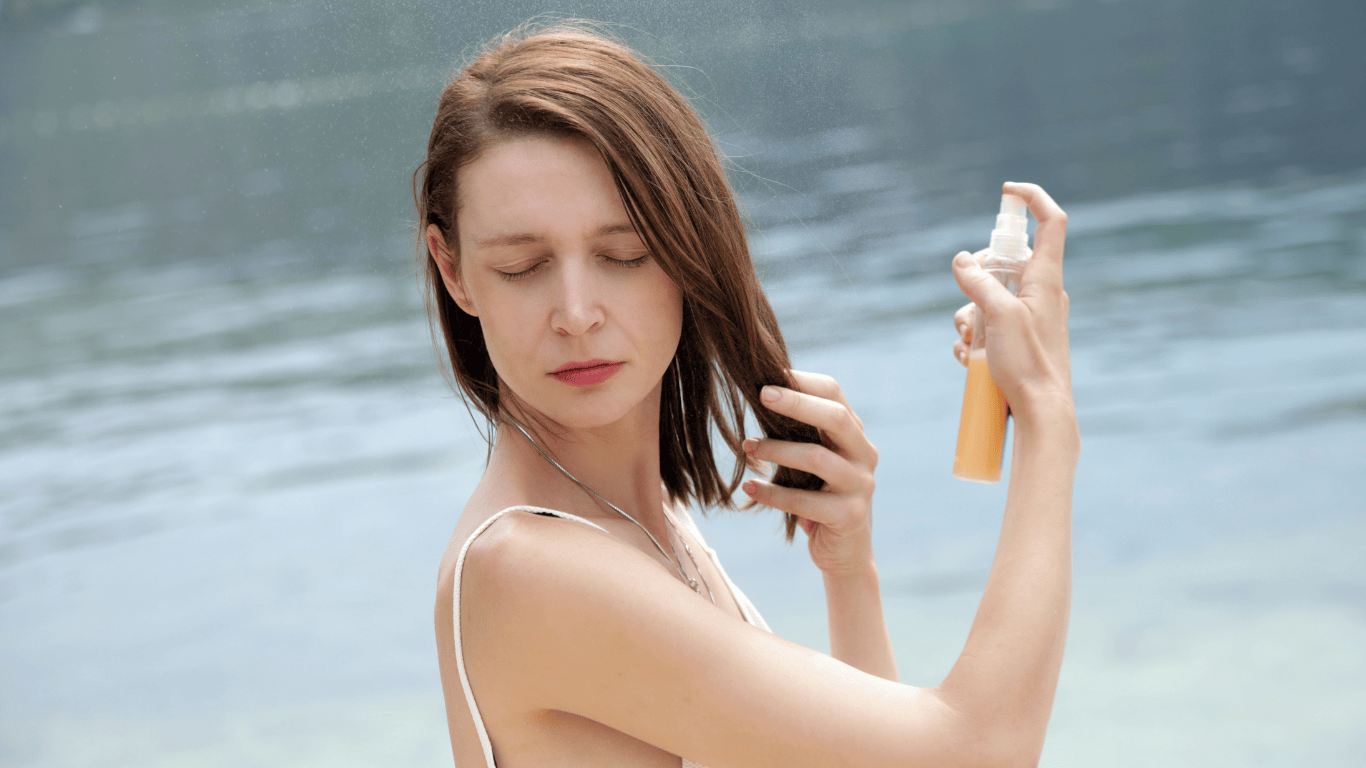 Mujer aplicándose protección solar capilar